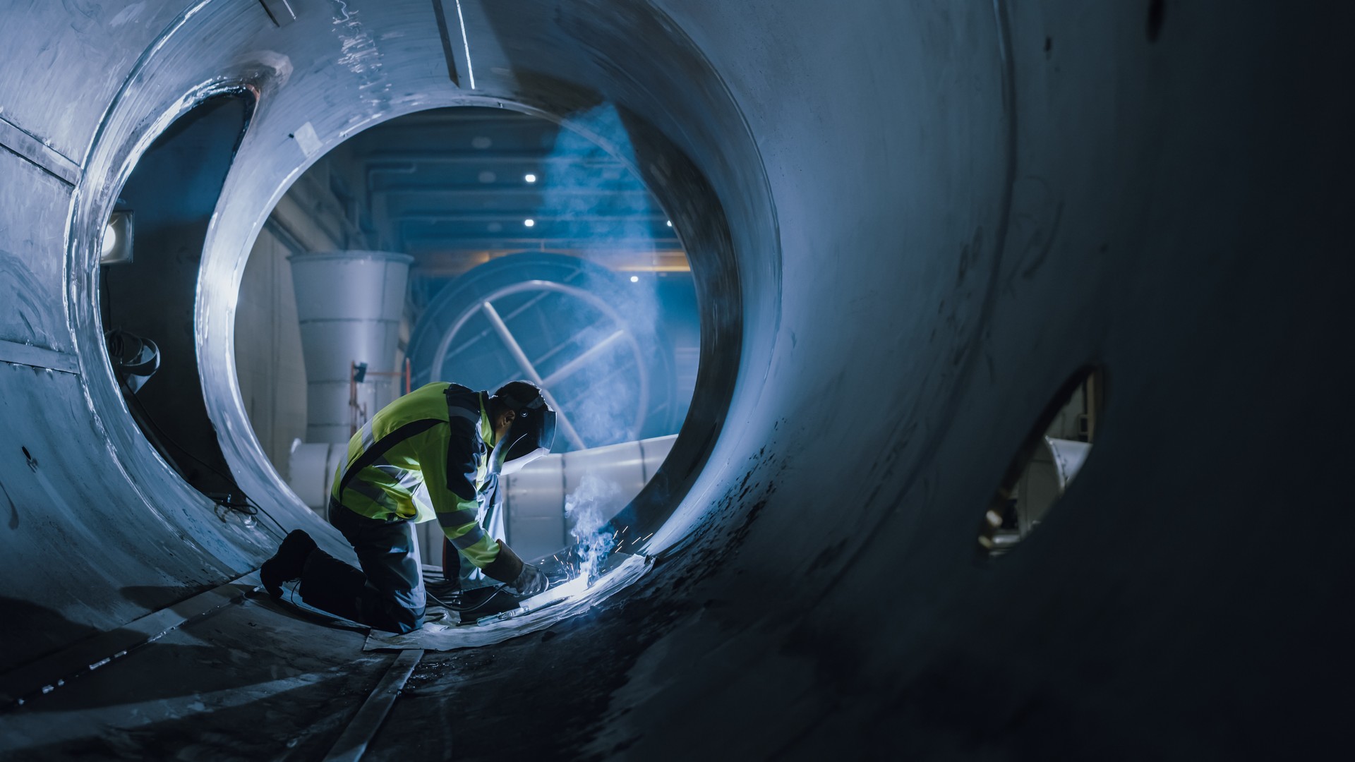 Professional Heavy Industry Welder Working Inside Pipe, Wears Helmet and Starts Welding. Construction of the Oil, Natural Gas and Fuels Transport Pipeline. Industrial Manufacturing Factory